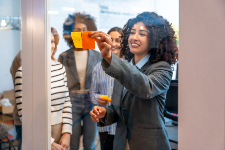 Hispanic woman and colleagues during brainstorming how to create a winning sales pipeline process using sticky notes